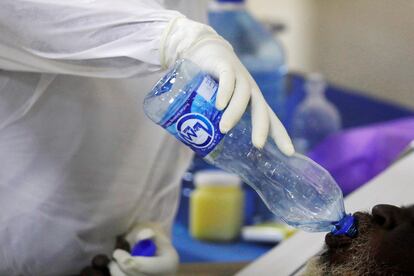 Un miembro del personal médico vestido con un traje protector proporciona agua a un paciente con covid-19 en la UCI del Hospital Machakos .