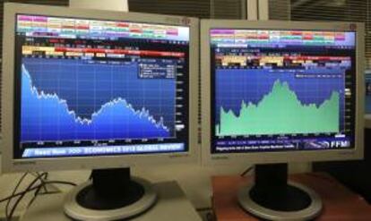 Pantallas que muestran la evolución del índice de referencia del mercado nacional, IBEX 35 (i), y la prima de riesgo. EFE/Archivo