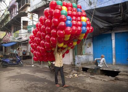 Un vendedor de globos recorre las calles de Allahabad (India) camino de un mercado donde venderlos.