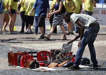 Un vendedor ambulante con una muestra de bolsos falsos.