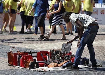 Un vendedor ambulante con una muestra de bolsos falsos. 