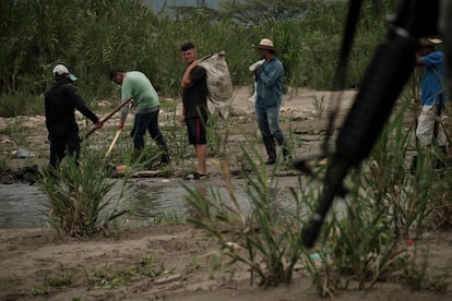 Personas trabajan en las trochas cerca al río Táchira mientras el ejército de Colombia patrulla la zona, el 29 de marzo.