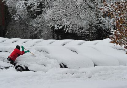 Un hombre quita el hielo de su vehículo aparcado en una calle de Epsom, al sur de Inglaterra.