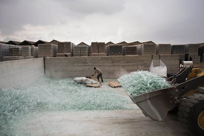 In this Wednesday, Jan. 27, 2016 photo, a worker breaks defective glass bottles to be recycled at the Phoenicia Glass Works Ltd. factory in the southern Israeli town of Yeruham. Phoenicia Glass Works Ltd. produces a million bottles and containers a day for beverage giants Coca Cola, Pepsi, and Heineken, as well as Israeli wineries and olive oil companies. Every day, about 300,000 bottles come out of the ovens with defects. (AP Photo/Oded Balilty)