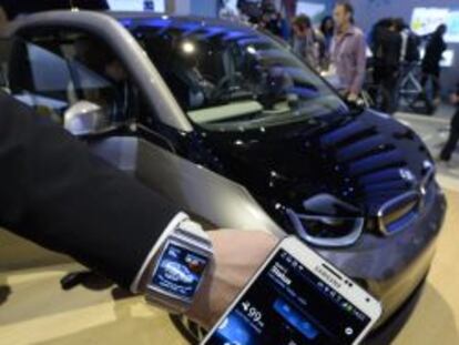 Un expositor del CES muestra un tel&eacute;fono y un reloj inteligente Samsung mientras estos interact&uacute;an con un veh&iacute;culo el&eacute;ctrico BMW 3i. 