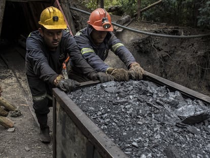 Dos mineros empujando un vagón de carbón afuera de una mina en Cucunuba (Colombia)