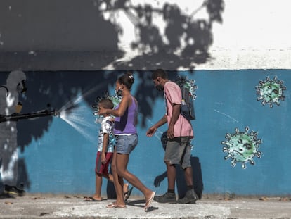 Una familia pasa por delante de un grafiti que muestra a un sanitario rociando coronavirus con la cara del presidente Jair Bolsonaro, el 22 de junio.