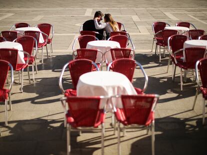 Dos turistas se sientan en una terraza vacía en la plaza de San Marcos en Venecia.