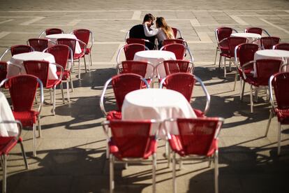 Dos turistas se sientan en una terraza vacía en la plaza de San Marcos en Venecia.