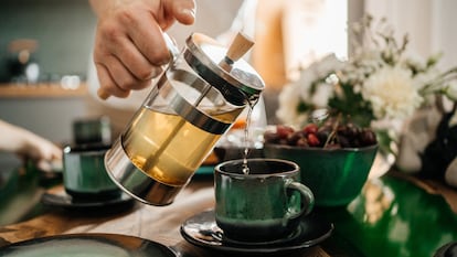 Una persona sirve un té recién elaborado en una taza.