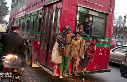 Niños de la calle de Bangladesh se cuelgan de un autobús en movimiento en Dhaka (Bangladesh).