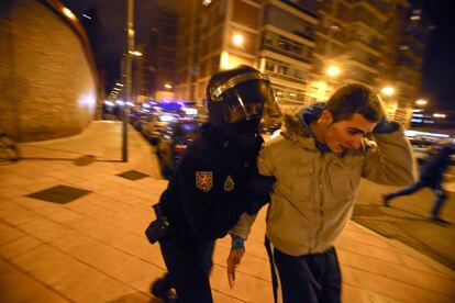 Un policía se lleva detenido a un joven, en los disturbios que tuvieron lugar la noche del lunes.