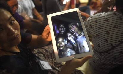 Uma familiar mostra uma foto de alguns dos desaparecidos tirada dentro da gruta pelas equipes de resgate nesta segunda-feira, na Tailândia. 