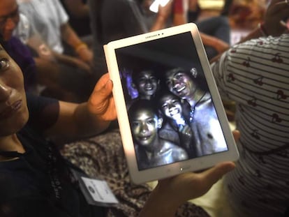 Uma familiar mostra uma foto de alguns dos desaparecidos tirada dentro da gruta pelas equipes de resgate nesta segunda-feira, na Tailândia. 