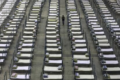 Un trabajador camina entre las camas de un centro de convenciones que se ha convertido en un hospital improvisado en Wuhan (China), epicentro de la epidemia del coronavirus que ha causado más de 700 víctimas mortales en China.