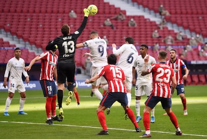 El portero del Atlético de Madrid, Jan Oblak, despeja con el puño el balón ante Benzema y Nacho.