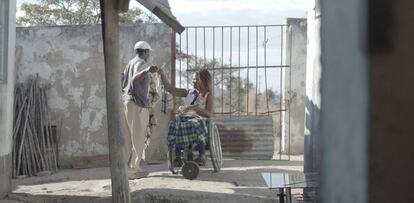 Una mujer en silla de ruedas tiende la ropa, junto con su hermano, en su vivienda en Goromonzi.