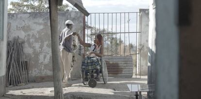 Una mujer en silla de ruedas tiende la ropa, junto con su hermano, en su vivienda en Goromonzi. 