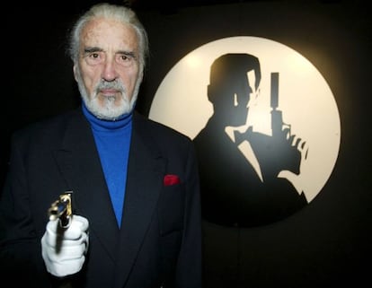 Christopher Lee, posa con la pistola original ante un cartel de la película 'El hombre de la pistola de oro' (1974).