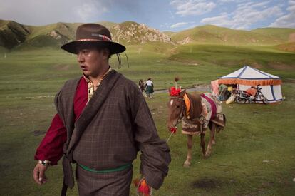 Un jinete nómada tibetano camina junto a su caballo en la meseta tibetana, en el condado de Yushú (China). 