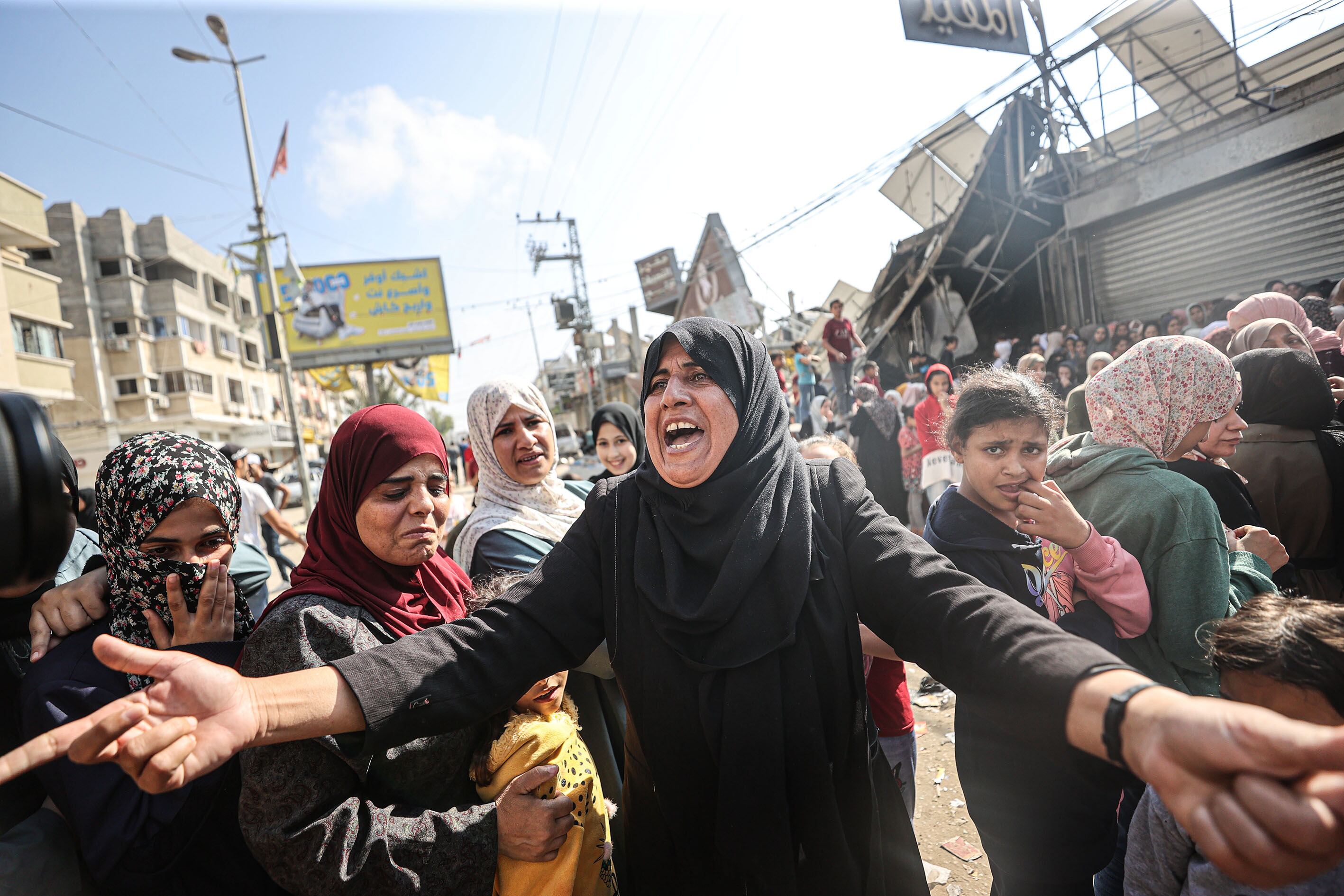 Una multitud hace cola para comprar en una panadería parcialmente destruida por un ataque israelí, este jueves, en el campo de refugiados de Nuseirat en  Deir al-Balah.