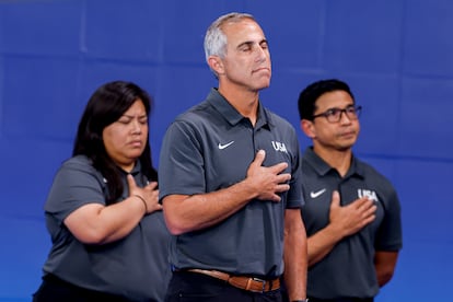 El entrenador de Estados Unidos, Adam Krikorian (centro),  escucha el himno nacional momentos antes del partido del Grupo B de waterpolo femenino entre Grecia y Estados Unidos, el 27 de julio.