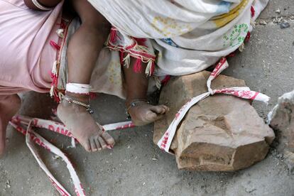 Sarta Kalara feeds her 15-month-old Shivani as one end of a barrier tape is tied to Shivani's foot and the other end to a stone to prevent Shivani from running away, when she works at a construction site nearby, in Ahmedabad, India, April 19, 2016. Kalara says she has no option but to tether her daughter Shivani to a stone despite her crying, while she and her husband work for 250 rupees ($3.8) each a shift digging holes for electricity cables in the city of Ahmedabad. There are about 40 million construction workers in India, at least one in five of them women, and the majority poor migrants who shift from site to site, building infrastructure for India's booming cities. Across the country it is not uncommon to see young children rolling in the sand and mud as their parents carry bricks or dig for new roads or luxury houses. REUTERS/Amit Dave       SEARCH "TIED TODDLER" FOR THIS STORY. SEARCH "THE WIDER IMAGE" FOR ALL STORIES