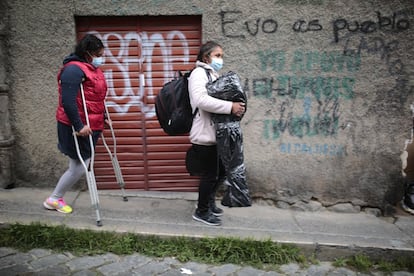 La Paz, Bolivia, 15 de septiembre de 2021: Míriam, la madre de Paola, camina delante de su hija portando por fin la nueva prótesis de la joven en una bolsa de plástico, mientras se dirigen a tomar un autobús a Uyuni. Míriam asegura que, sin el apoyo de la gente de su comunidad, no hubieran logrado nada de esto. Ella es ama de casa y comerciante: vende productos que importa de Chile. Durante la pandemia pasaron momentos muy difíciles, ya que Uyuni es altamente turístico y, al no haber visitantes por la covid-19, la economía se vio muy dañada.