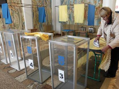 Una mujer plancha unas cortinas en un centro electoral.