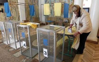 Una mujer plancha unas cortinas en un centro electoral.