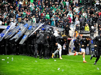 Jugadores y antidisturbios escapan durante los incidentes violentos dirigidos contra el equipo kurdo Admespor, mientras se lanzan objetos al campo en un partido de fútbol entre el equipo de fútbol turco Bursaspor y el Amedspor de Diryabakir, en Bursa el 5 de marzo de 2023.