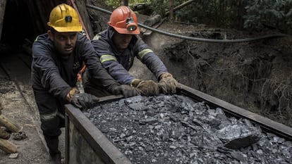 Dos mineros empujando un vagón de carbón afuera de una mina en Cucunuba (Colombia)