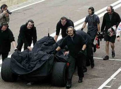 Los mecánicos de McLaren empujan el coche junto a Fernando Alonso.