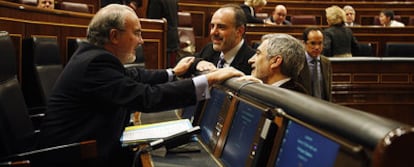 El ministro de Economía, Pedro Solbes, charla con Gaspar Llamazares y Joan Ridao ayer en el Congreso.