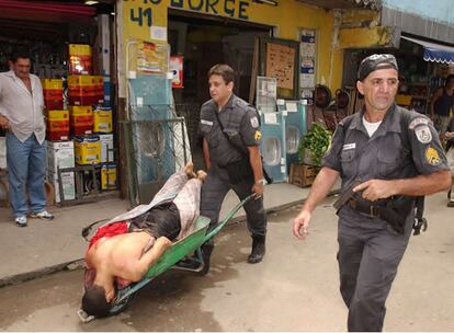 Policías transportan en una carretilla el cadáver de uno de los ocho muertos en un tiroteo con bandas de traficantes de droga, en la favela Rocinha. Abril de 2004