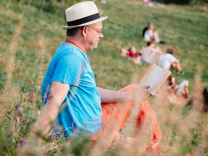 A man reads in Berlin's Mauerpark, with the Alexanderplatz television tower in the background.