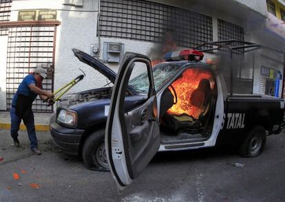 Un manifestante destruye un coche de polic&iacute;a en Chilpancingo. 