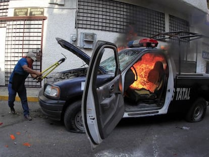 Un manifestante destruye un coche de polic&iacute;a en Chilpancingo. 