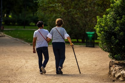 Una persona mayor da un paseo por el parque El Retiro acompañada de una mujer.