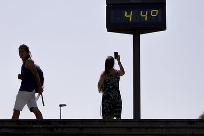 Una mujer toma hoy una fotografía de un termómetro que marca 44 grados junto al Puente del Cachorro, en Sevilla.