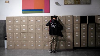 Un alumno saca los libros de texto de su taquilla en una biblioteca.