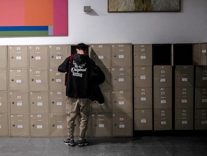 Un alumno saca los libros de texto de su taquilla en una biblioteca.