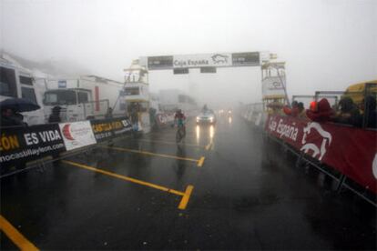 Vinokurov cruza la meta en Navacerrada, ayer, entre la niebla y la lluvia.