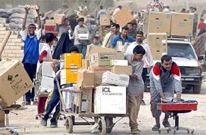 Ciudadanos de Bagdad llevan en carros el botín del saqueo a un almacén estatal en la capital iraquí.