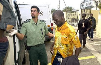 Un guardia civil conduce a un furgón a varios de los inmigrantes detenidos al sur de Fuerteventura.