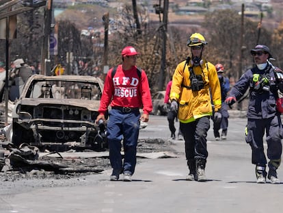Members of a search-and-rescue team walk along a street, Saturday, Aug. 12, 2023, in Lahaina, Hawaii, following heavy damage caused by wildfire. (AP Photo/Rick Bowmer)