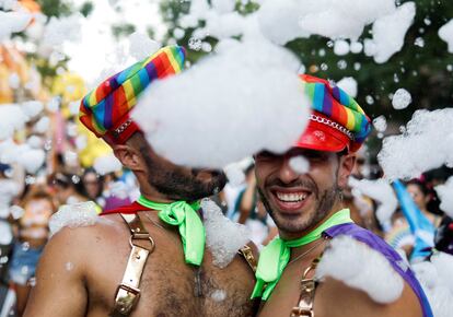 Dos hombres se refrescan con espuma en la marcha del orgullo en Madrid.