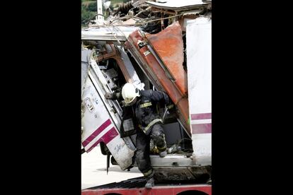 Un bombero sale de uno de los vagones accidentados, deformado por la fuerte colisi&oacute;n. 