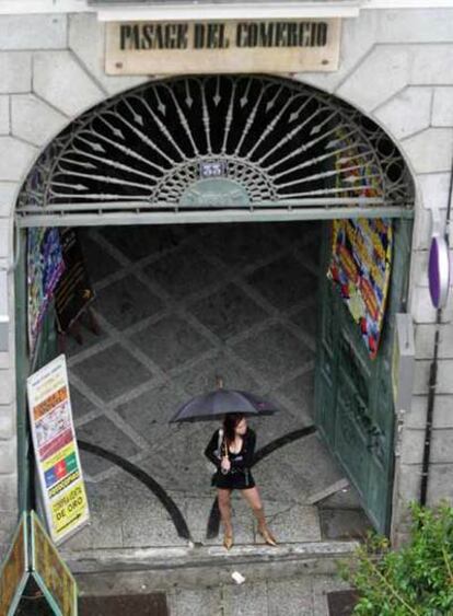 Una prostituta se refugia de la lluvia en la entrada del pasaje del Comercio.