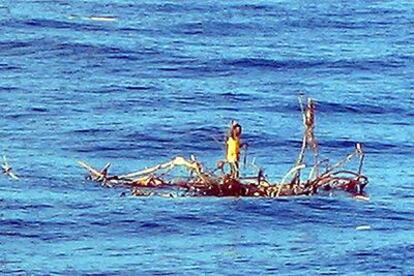 El náufrago Rizal Shahputra, de pie sobre las ramas de un árbol, hace señales al barco mercante que le salvó en el océano Índico.